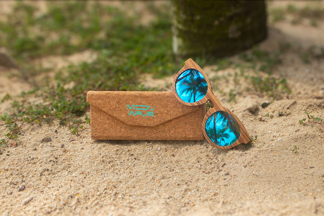 MoovWave BlooWave Glacier wooden floatable polarized sunglasses with blue mirrored lenses on sandy beach with cork case
