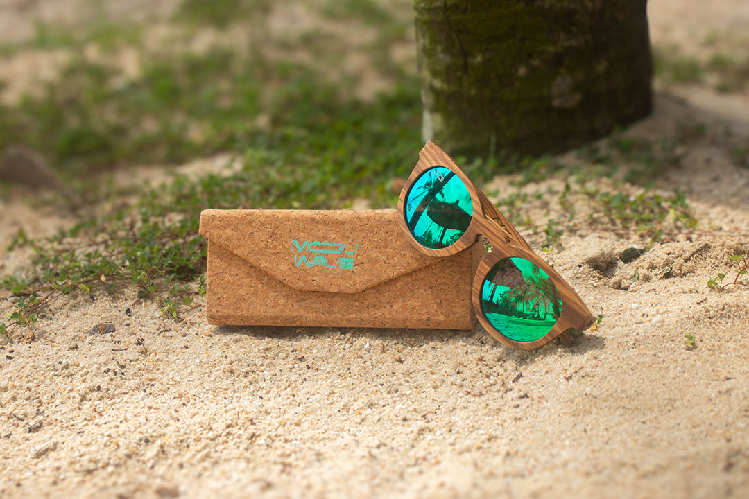 MoovWave BlooWave Jade wooden floatable polarized sunglasses with green mirrored lenses on sandy beach with cork case